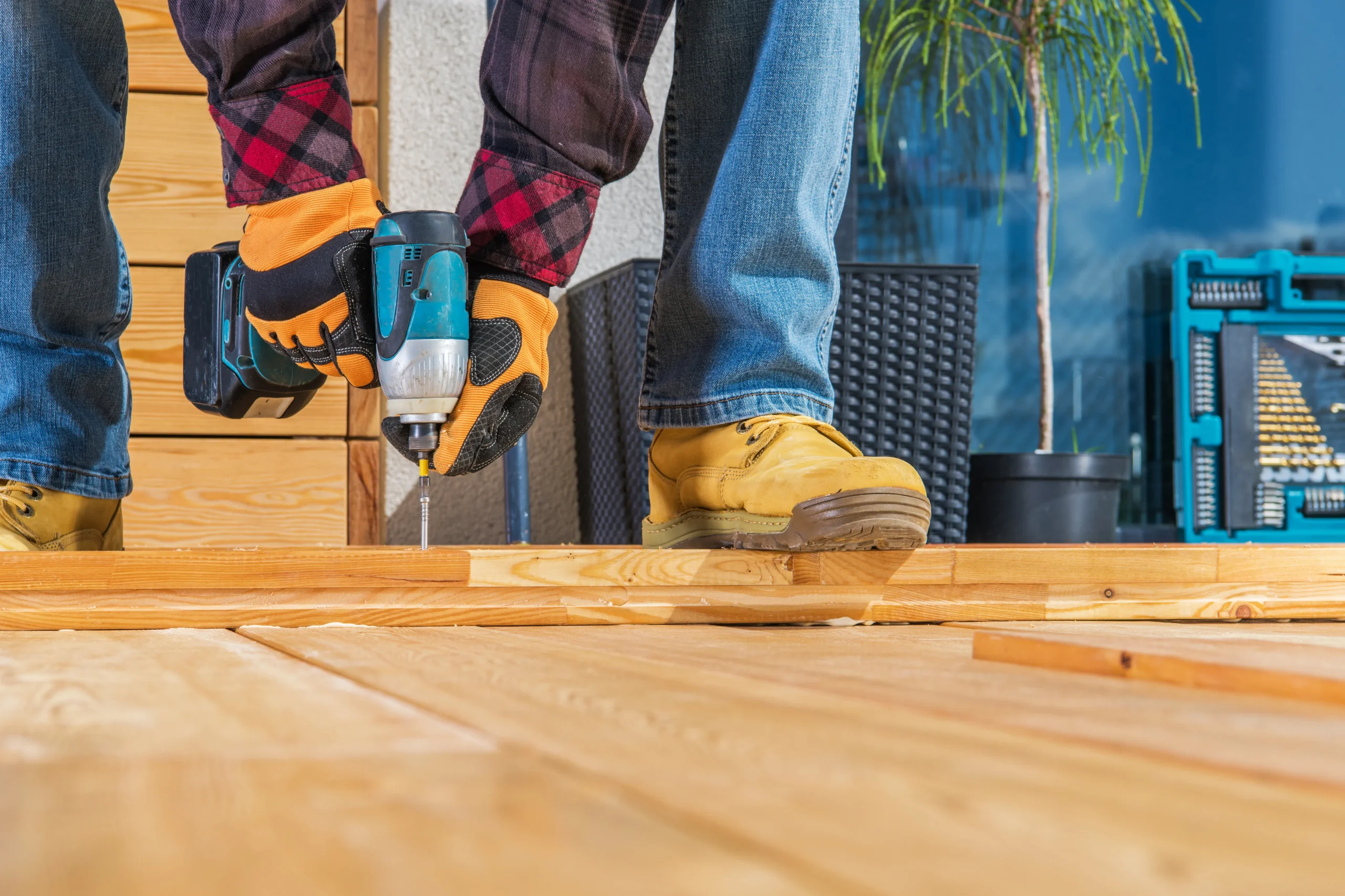 Cómo remodelar una casa: fotografía de una persona utilizando guantes y botas de seguridad mientras instala un piso.